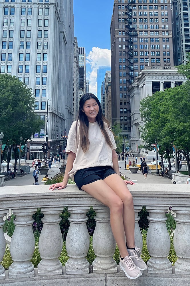 Katherine Park sitting on a decorative ledge in a city.