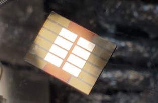 photo of organic solar cell devices on a substrate, showing eight white rectangles in two columns on top of a single large beige rectangle.