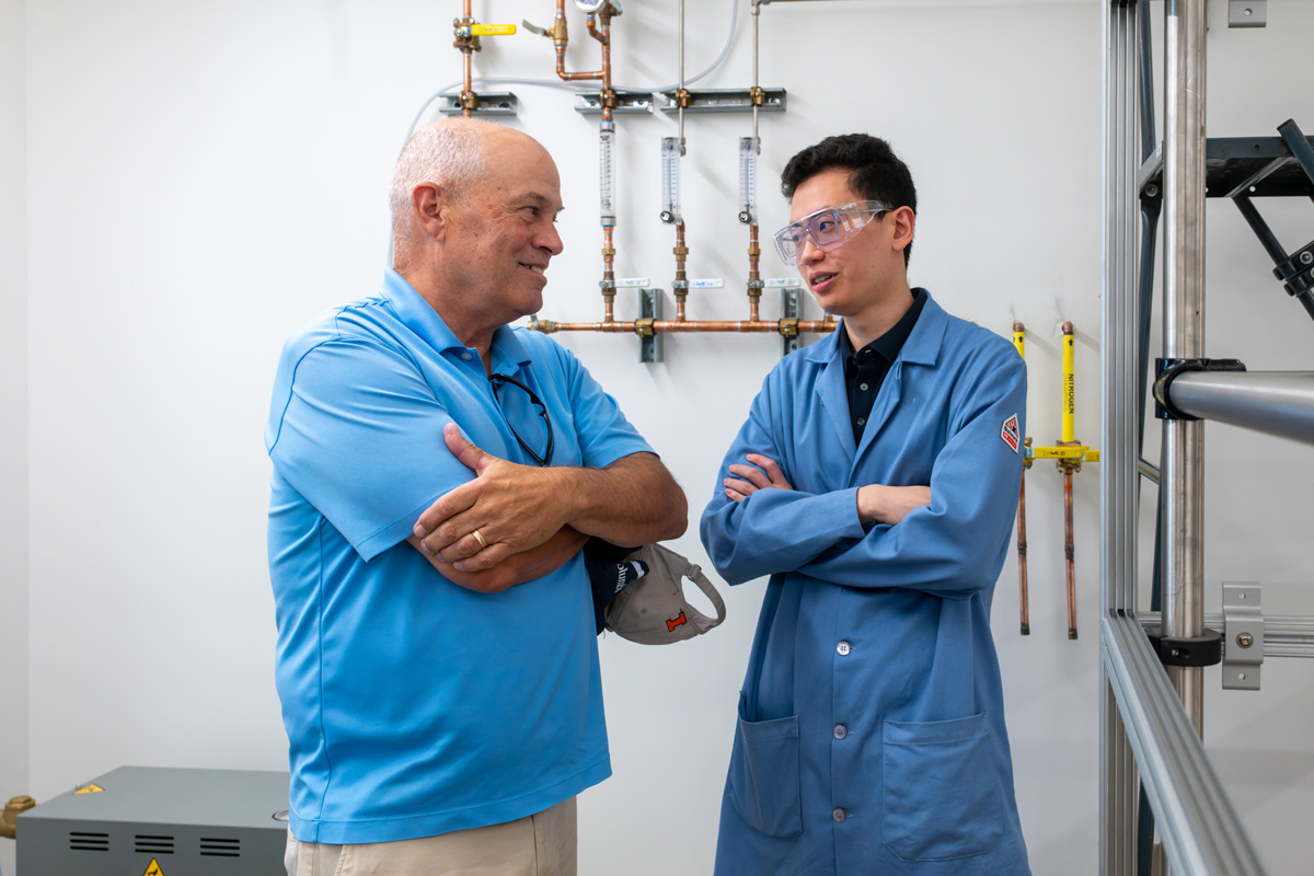 student and alumnus next to the distillation column