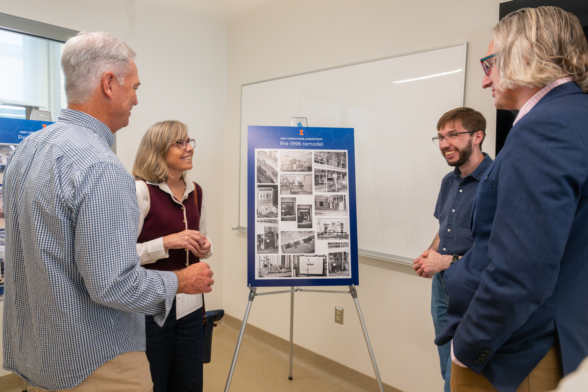 four people standing in front of a poster with historical photos of the lab