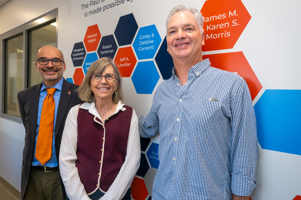 two men and a woman standing in front of a blue and orange wall art