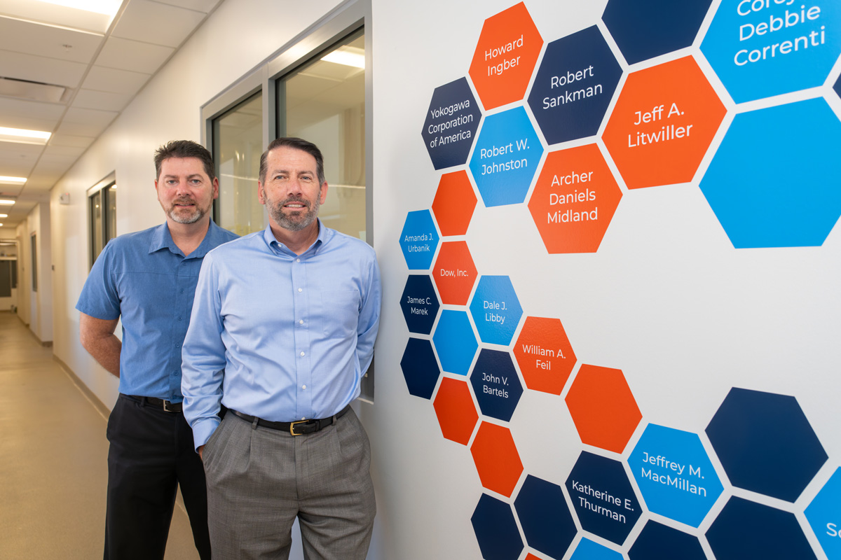 two men standing in front of blue and orange wall art