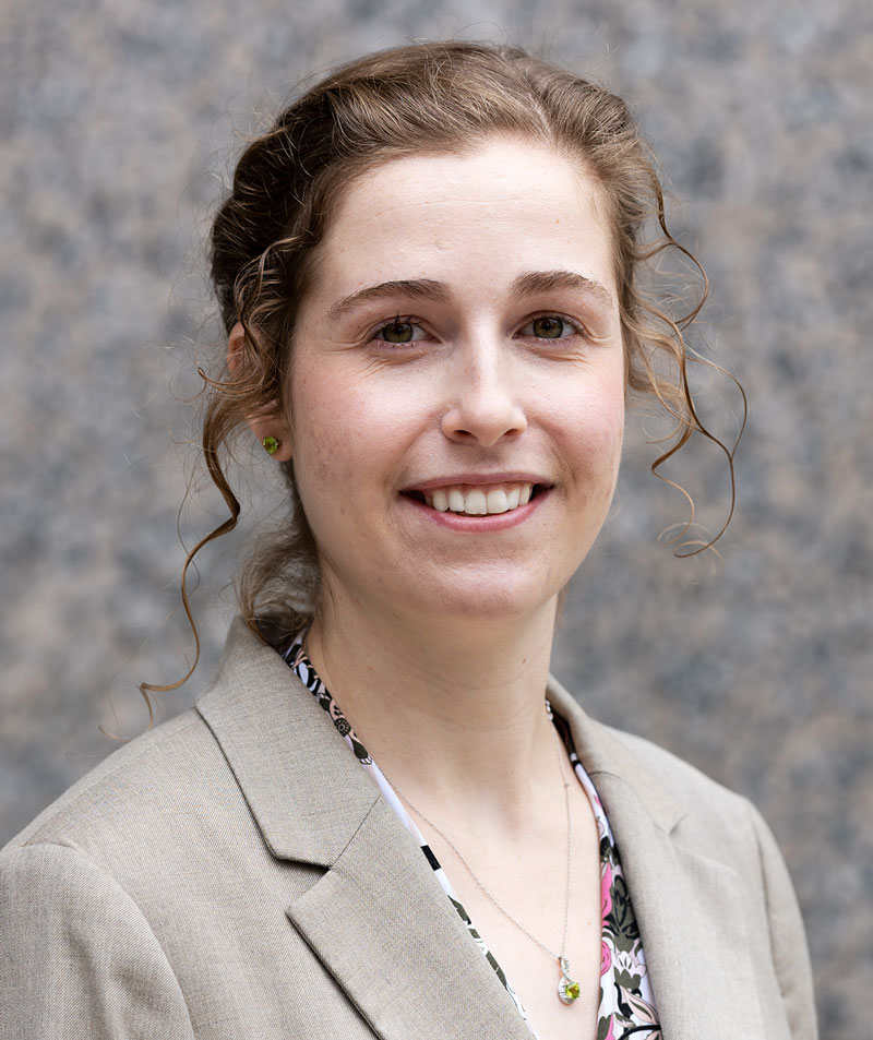 a smiling woman standing in front of a blurry gray background