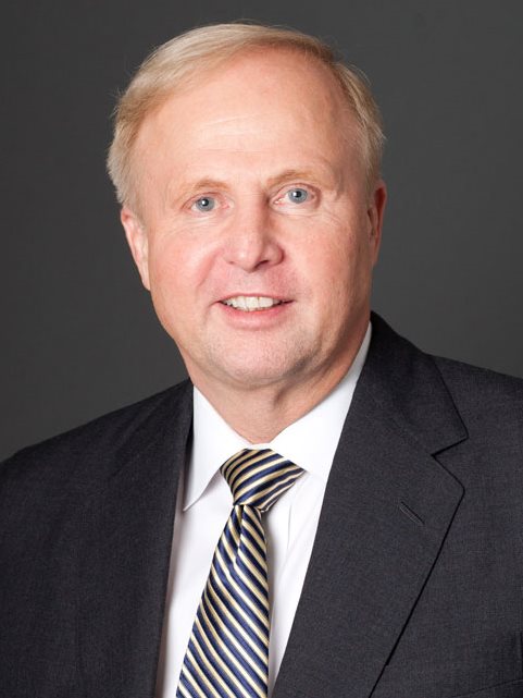 A man wearing a black suit is smiling for the photo.