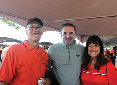 Two men and a woman wearing Illinois attire in the event tent