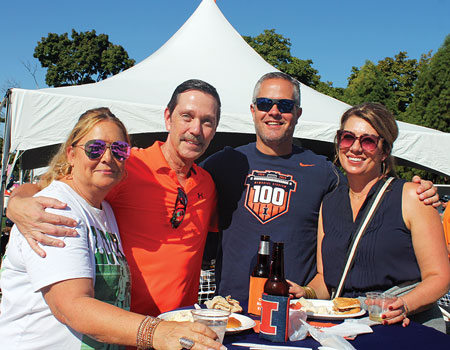 Two men and two women wearing Illinois attire and smiling at the camera.
