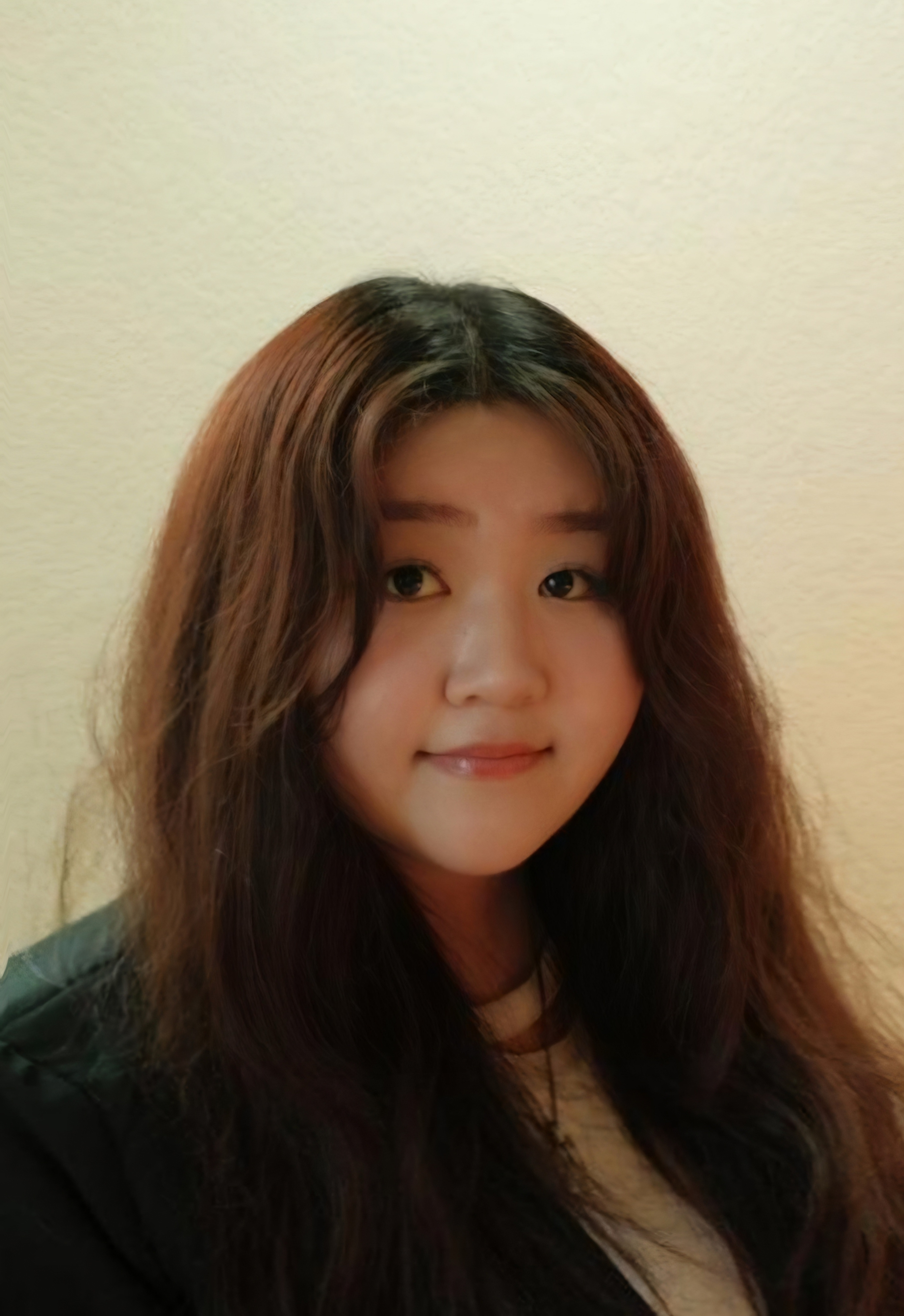 A young woman wearing a black suit jacket poses for a professional photo.