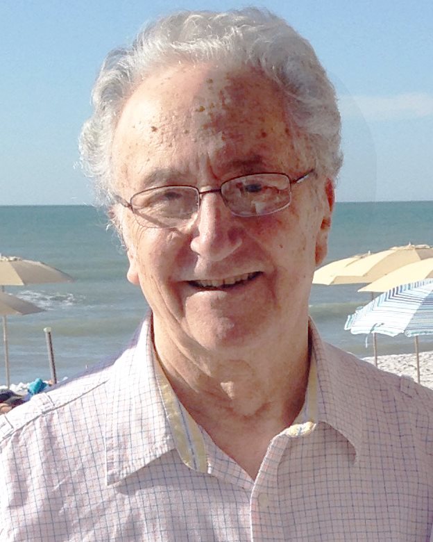 Joe standing on a beach with the ocean behind him