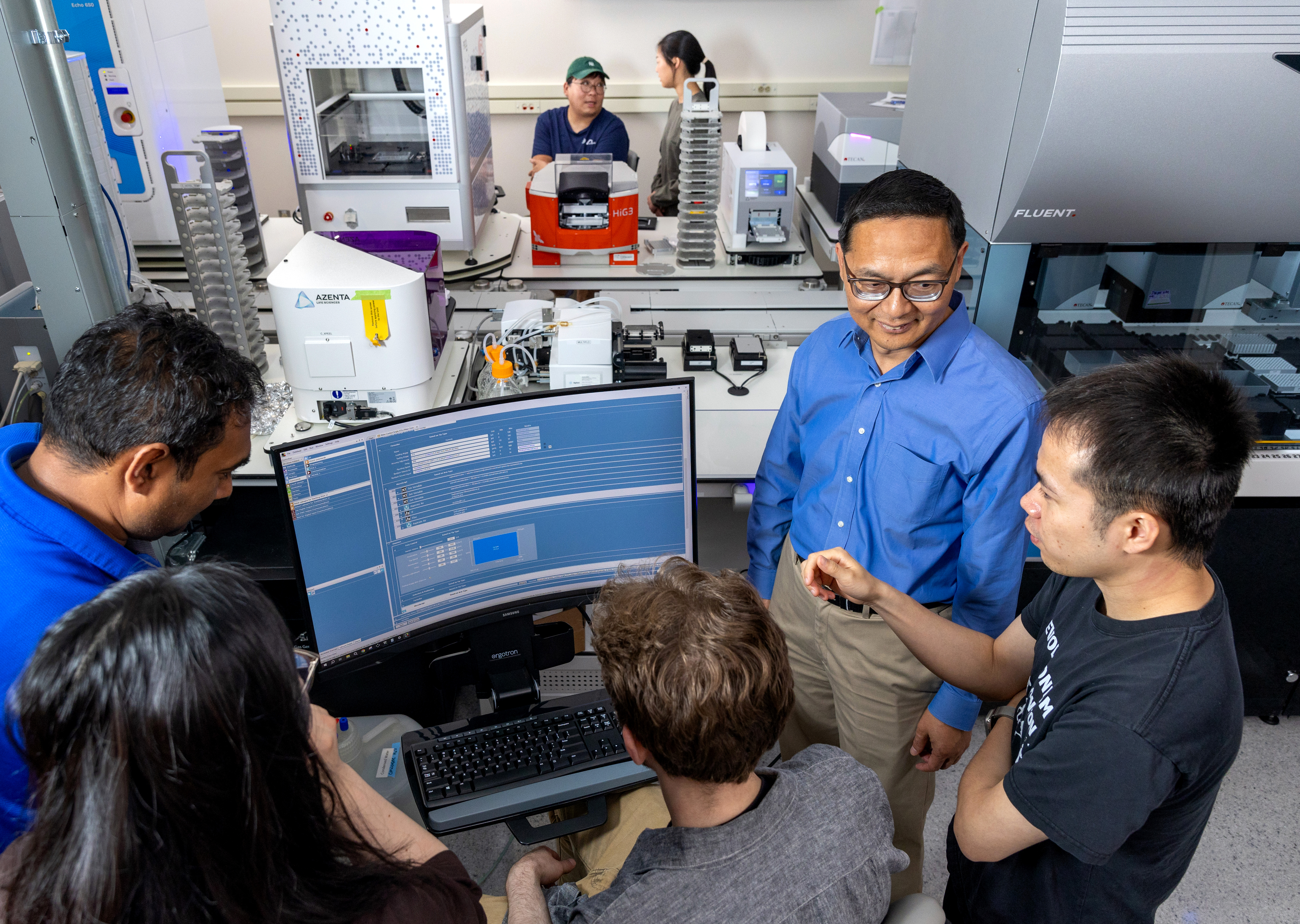 A group of individuals enagage in a conversation while surrounding a computer.