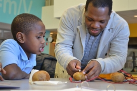 Lecturer Dr. Jerrod Henderson helps a youngster with his potato battery during one of the program's sessions.