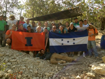 Illinois students poseâ€…withâ€…newlyâ€…trainedâ€…laborersâ€…fromâ€…Lasâ€…Queseras, Honduras,â€…andâ€…supportâ€…staffâ€…fromâ€…NGO partnerâ€…Aguaâ€…yâ€…Desarrolloâ€…Comunitarioâ€…inâ€…frontâ€…ofâ€…aâ€…newâ€…ferrocementâ€…waterâ€…storageâ€…tankâ€…thatâ€…theyâ€…jointlyâ€…builtâ€…duringâ€…aâ€…visitâ€…inâ€…Marchâ€…2014. 