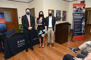 Laura Flessner stands with Paul Kenis and Chris Rao holding 2021 Alumni Award.