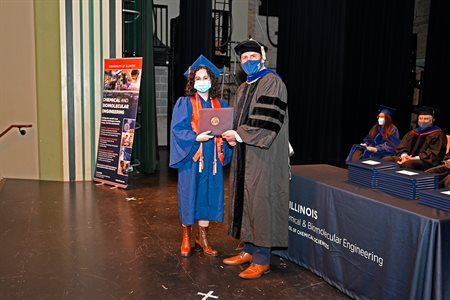 Sydney Butikofer receives her diploma cover from department head Paul Kenis.