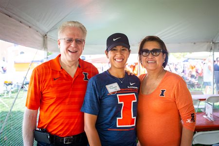 Laura Flessner with her parents at a tailgate wearing blue and orange.