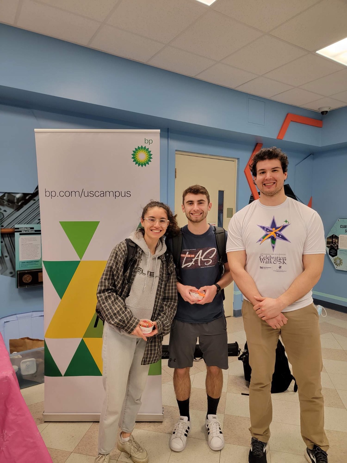 Three students who attended bp's information session stand next to bp banner.